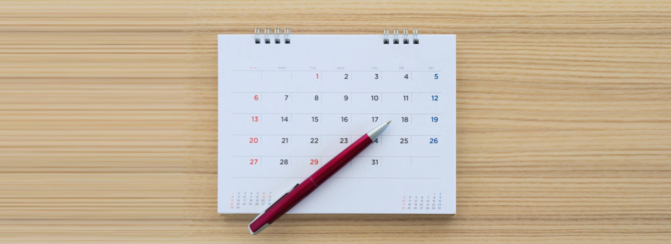 calendar page with pen on wood table background